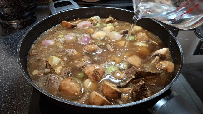 adding water to stew in pan