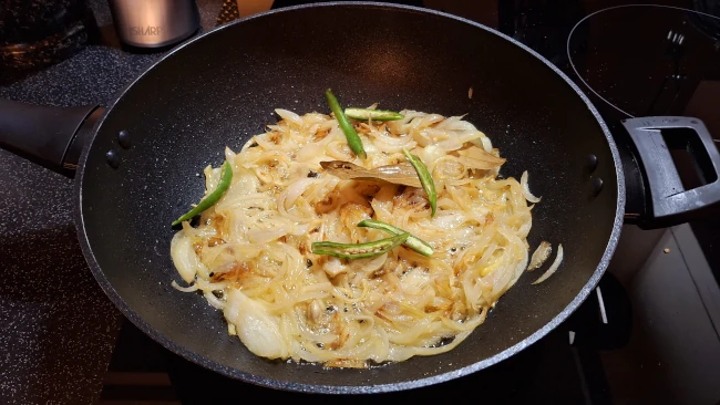 chillies added to browned onions for chicken biryani chillies added to browned onions