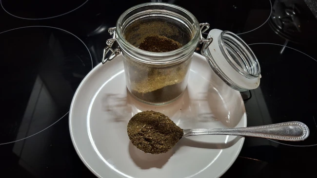 curry leaf masala on a spoon and in a storage jar curry leaf masala spoon and jar
