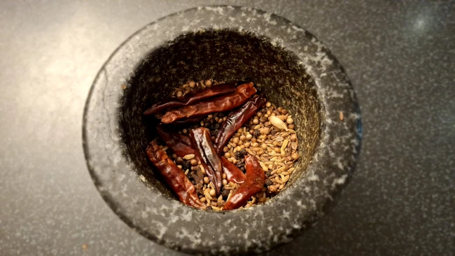 whole spices cooling in a mortar for curry leaf masala chicken fry whole spices cooling in a mortar