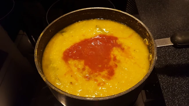 adding tomatoes to cooked dhal for dhal with fried spices tomatoes added to dhal in pan