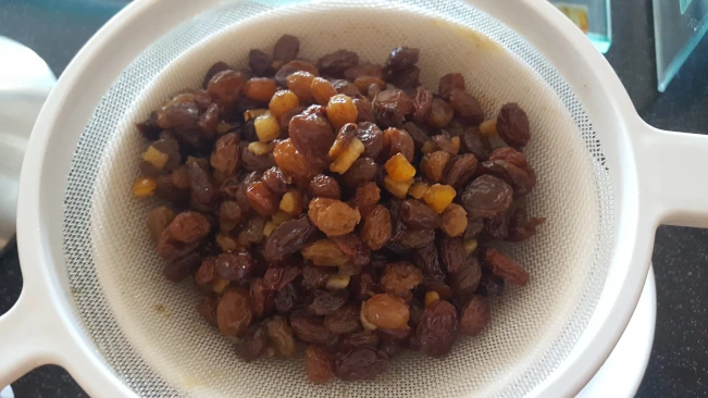 soaked dried fruit being drained in a sieve for the fruit cake soaked fruit drained in a sieve