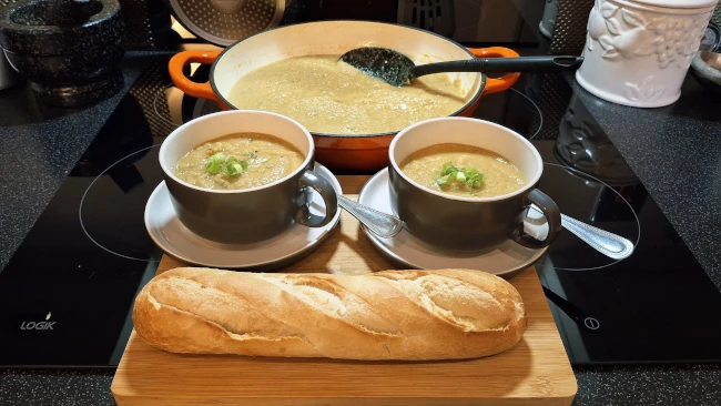 two bowls and a pan of jamaican pumpkin soup