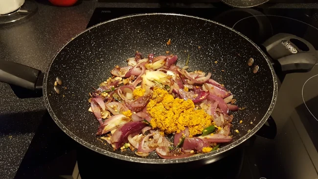 spice paste added to the onions in a wok spice paste added