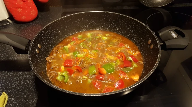 peppers added to pan for lamb curry with spinach peppers added to pan