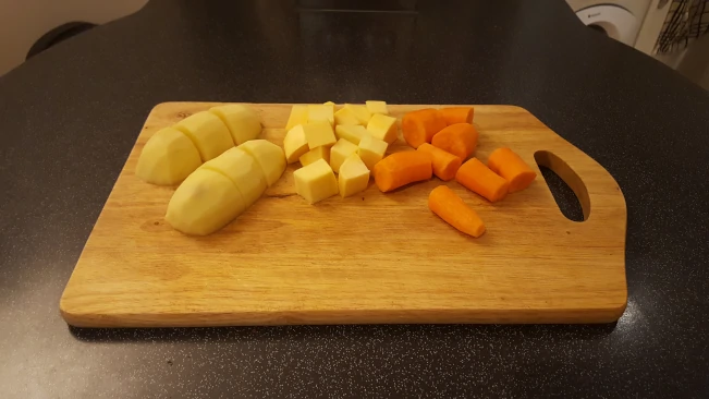 potatoes carrots swede on chopping board