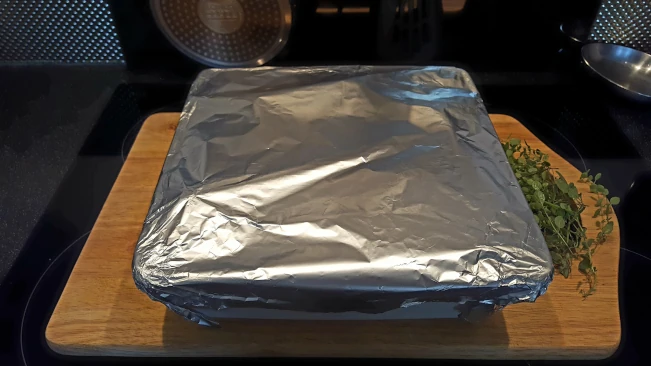 ingredients covered in foil for Mediterranean style vegetables with pork steaks foil covered oven dish 01