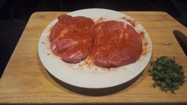 raw seasoned pork steaks on a plate for Mediterranean style vegetables with pork steaks raw seasoned pork steaks on a plate
