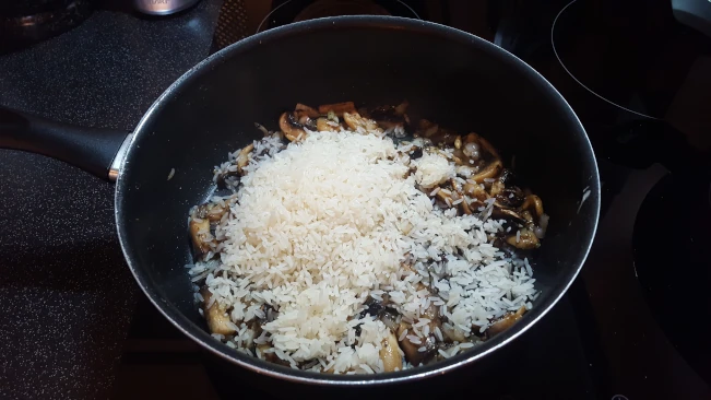 rice added to mushrooms in a pan for mushroom fried rice rice added to mushrooms