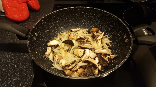 mushrooms added to the onions in a wok mushrooms added