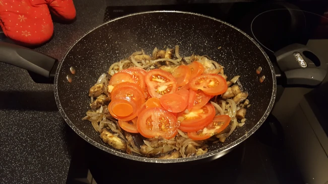 tomatoes added to onions in a wok tomatoes added