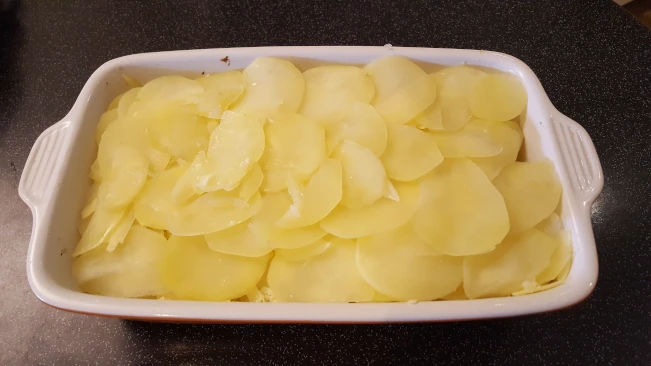 sliced potatoes added to dish for smoked haddock bacon bake sliced potato gratin