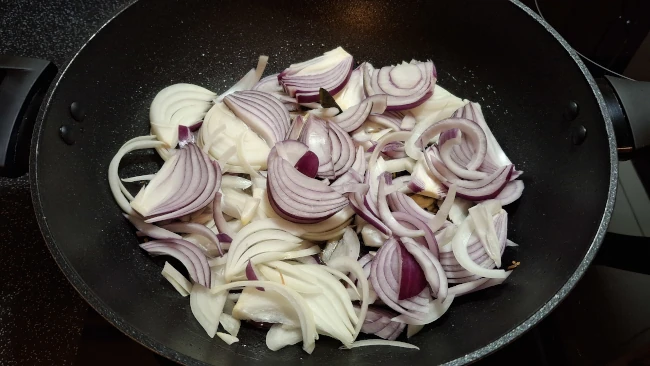 sliced onions in a wok for spicy balti potatoes sliced onions in a wok