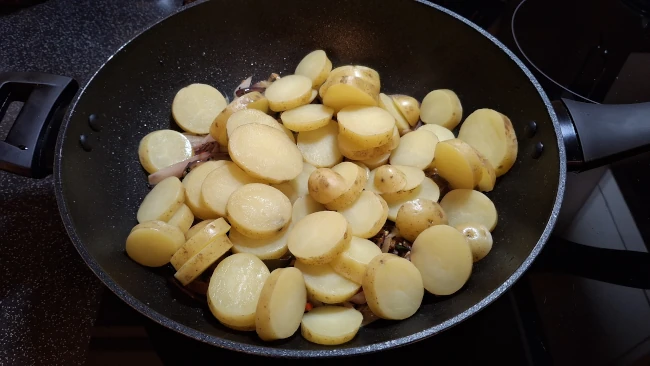 sliced potatoes added to wok for spicy balti potatoes sliced potatoes added to wok