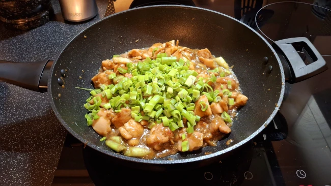 green onions added to fried chicken in wok