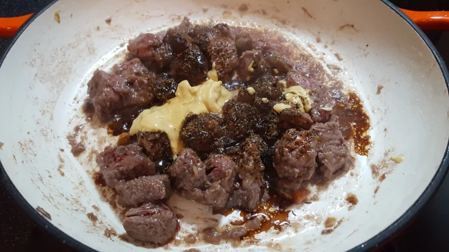 mustard and seasoning added to steak