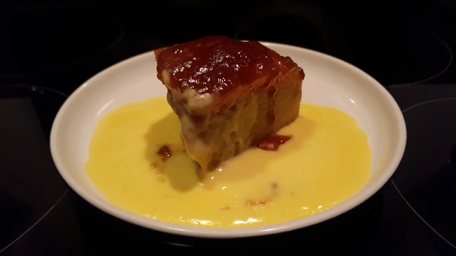 a slice of strawberry jam steamed sponge pudding custard a slice of steamed pudding and custard
