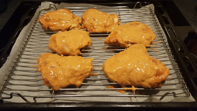 raw tandoori chicken on grill rack